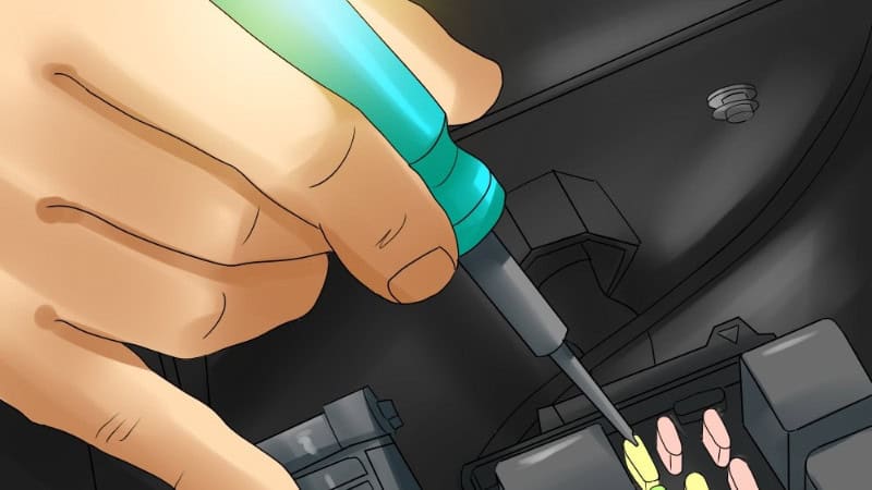 Close-up of a mechanic inspecting car fuses and relays inside the fuse box using a fuse puller.